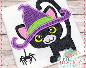 Puede incluir: Gato negro con un sombrero de bruja morado con un borde verde y sosteniendo una araña negra. El gato tiene orejas rosas y ojos amarillos. La imagen está sobre un fondo blanco.
