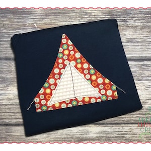 May include: A navy blue fabric with a red, yellow, and green patterned triangle applique of a tent. The tent has a white fabric flap with a white stitched design.
