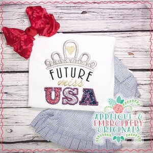 Puede incluir: Camiseta blanca con una corona, las palabras "Future Miss USA" y un corazón. Las letras de USA están hechas de tela colorida.