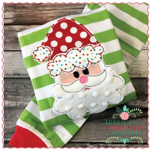May include: Green and white striped fabric with a white, red, and blue applique of Santa Claus's face. The applique has a white beard, red hat with white trim, and a pink nose.