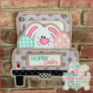 May include: A gray and white truck with a bunny rabbit in the bed. The truck has a sign that says "Hoppy Easter".
