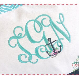 May include: A teal blue embroidered monogram with the letter "A" and an anchor with flowers. The anchor is black with pink and white flowers. The background is white.