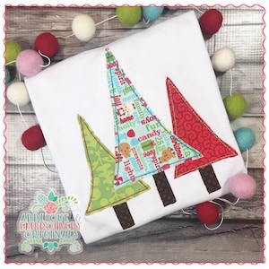 May include: Two Christmas trees made of fabric with a variety of Christmas-themed words and designs. The trees are green and red and have brown trunks. The trees are on a white background.