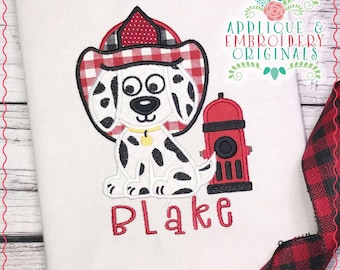 Op de afbeelding: Geborduurde afbeelding van een Dalmatiër die een rood-wit geblokte brandweerhelm draagt, zittend naast een rode brandkraan. De naam "Blake" is geborduurd onder de hond en de brandkraan.
