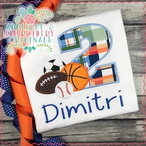 May include: A white t-shirt with a blue number 2, a blue and white plaid pattern, and a group of sports balls including a soccer ball, basketball, football, and baseball. The name Dimitri is embroidered in blue below the number.