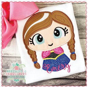 May include: Embroidered design of a cartoon girl with brown hair in braids, wearing a blue and pink dress. The name "Emery" is embroidered below the girl.