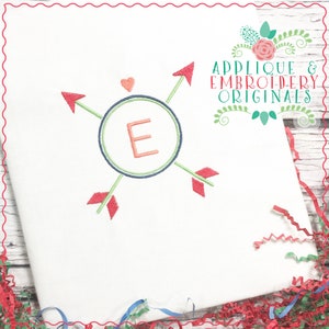 May include: Embroidered design featuring a circle with the letter "E" inside, surrounded by four arrows pointing in different directions. The design is in shades of red, green, and blue on a white background.