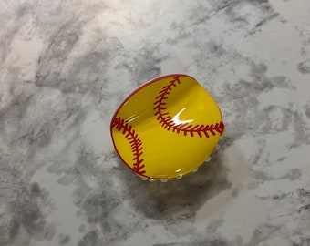 May include: A yellow softball with red stitching, painted on a ceramic dish.