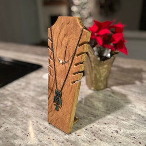 May include: Wooden necklace stand with two necklaces, one with a pearl pendant and the other with an owl pendant.