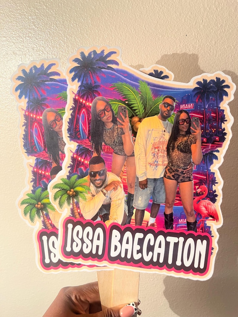 May include: A decorative cake topper featuring a vibrant Miami-themed background with palm trees, neon lights, and a flamingo. The design includes a photo of a couple and the text "IS ISSA BAECATION" in bold white letters on a pink and black background.