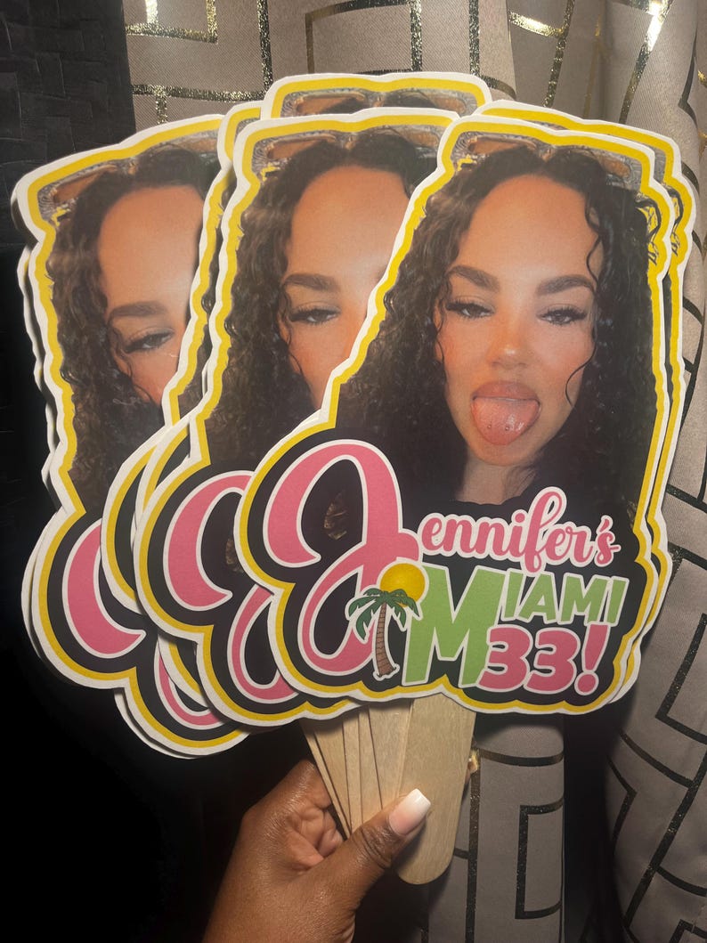 May include: Three identical custom die-cut paper fans featuring a photographic portrait of a person with curly dark hair sticking their tongue out. The text reads Jennifer's MIAMI 33! in pink and green, accompanied by a small palm tree graphic.