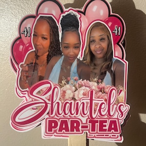 May include: A custom cake topper featuring three photographs of the same person, surrounded by pink balloons and floral accents. The text reads 'Shantel's PAR-TEA' with the number '41' displayed on both sides. The topper is attached to a wooden stick.