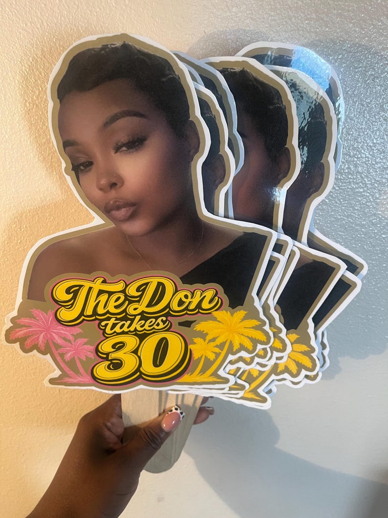 May include: A stack of custom die-cut cardstock cake toppers featuring a photographic portrait of a person with short dark hair. The design includes the yellow and black text The Don takes 30, accented by pink and yellow palm tree illustrations.