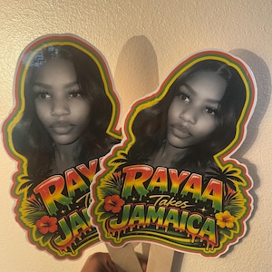 May include: Two custom handheld fans featuring a black and white portrait of a person. The design includes the text "RAYAA Takes JAMAICA" in a red, yellow, and green gradient font, surrounded by tropical palm tree and hibiscus flower graphics.