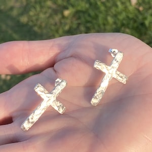 May include: A pair of silver hammered cross earrings. The earrings are simple and elegant, and would make a great gift for any occasion.