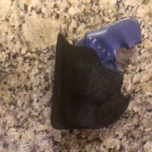 May include: A black holster with a blue object inside. The holster is made of a textured material. The blue object has the text "< CR 2" on it.