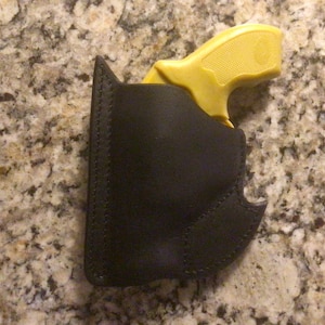 May include: A black leather holster for a small yellow handgun.