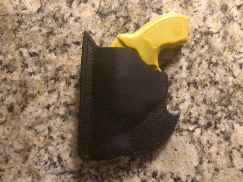 May include: A black leather holster for a small yellow handgun.