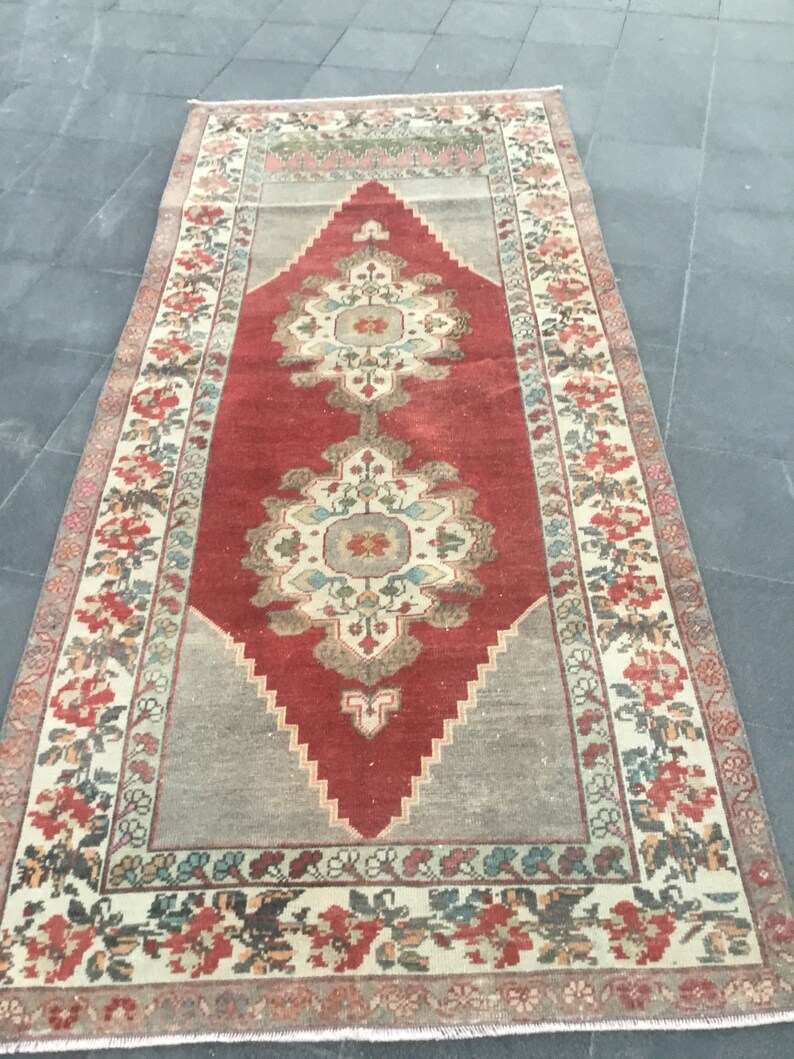 Puede incluir: Una alfombra vintage con un patr&oacute;n floral rojo, crema y azul. La alfombra tiene un centro en forma de diamante con un dise&ntilde;o floral y un borde con un patr&oacute;n floral.