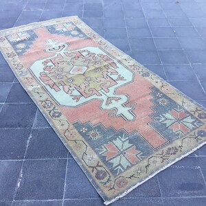 Puede incluir: Una alfombra vintage con un diseño persa tradicional. La alfombra tiene un fondo azul claro con un medallón central en tonos de rosa, verde y marrón. La alfombra tiene un borde con flecos.