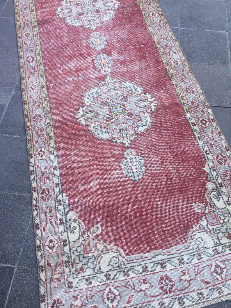Pode incluir: Um tapete corredor vermelho vintage com um padr&atilde;o floral desbotado e uma borda branca. O tapete tem um visual desgastado e &eacute; perfeito para adicionar um toque de estilo bo&ecirc;mio &agrave; sua casa.
