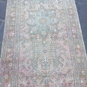 May include: A vintage pink and green runner rug with a traditional floral pattern. The rug has a faded, distressed look, giving it a unique and antique feel.