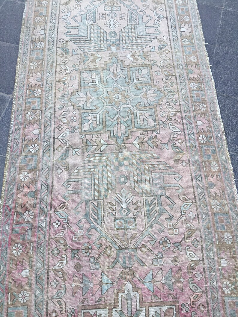 May include: A vintage pink and green runner rug with a traditional floral pattern. The rug has a faded, distressed look, giving it a unique and antique feel.