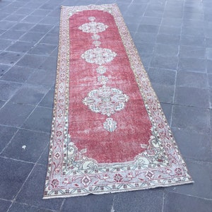 Pode incluir: Um tapete corredor vintage vermelho e creme com um padr&atilde;o floral. O tapete tem um visual desgastado e &eacute; perfeito para adicionar um toque de estilo bo&ecirc;mio &agrave; sua casa.