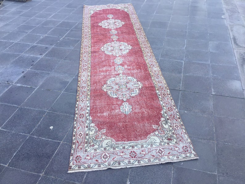 Pode incluir: Um tapete corredor vintage vermelho e creme com um padr&atilde;o floral. O tapete tem um visual desgastado e &eacute; perfeito para adicionar um toque de estilo bo&ecirc;mio &agrave; sua casa.