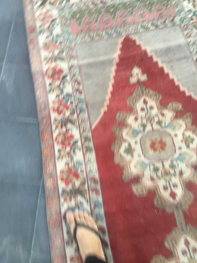 Puede incluir: Un primer plano de una alfombra roja, blanca y azul con un dise&ntilde;o floral. La alfombra tiene un aspecto desgastado y vintage.