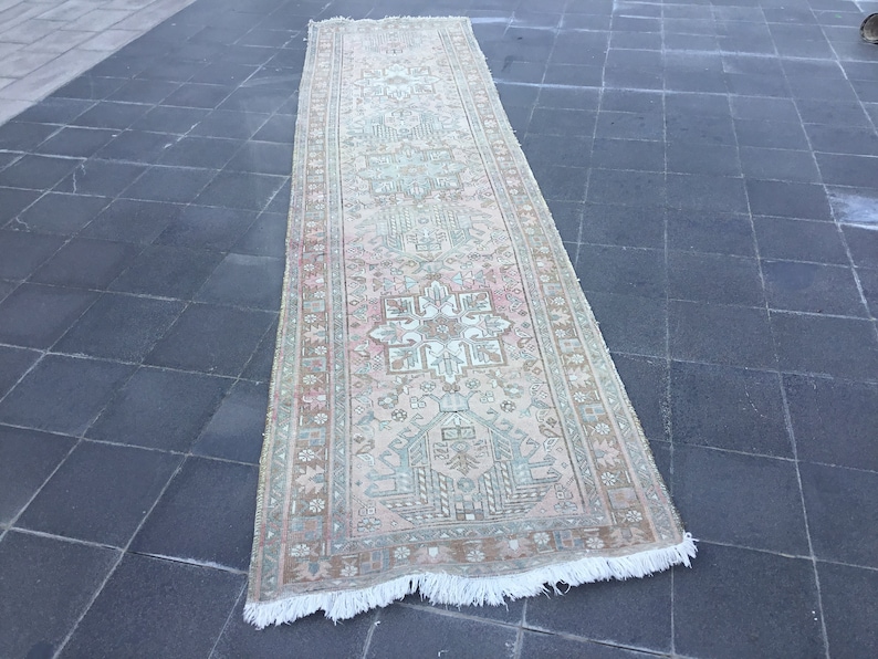 May include: A long, rectangular rug with a pink and green floral pattern. The rug has a white fringe on the edges.