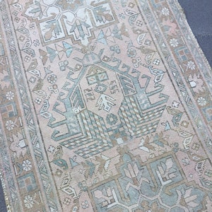 May include: A vintage Turkish rug with a faded pink background and intricate geometric patterns in shades of blue, green, and brown.