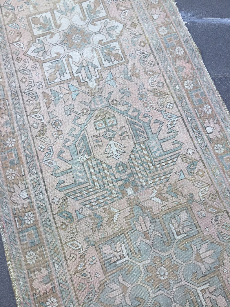May include: A vintage Turkish rug with a faded pink background and intricate geometric patterns in shades of blue, green, and brown.