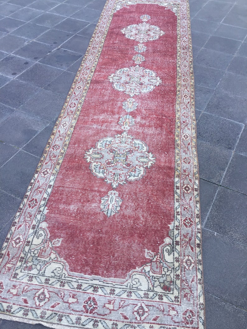 Pode incluir: Um tapete corredor vermelho vintage com um padr&atilde;o floral desbotado e uma borda branca. O tapete tem um visual desgastado e &eacute; perfeito para adicionar um toque de estilo bo&ecirc;mio &agrave; sua casa.