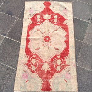 May include: A vintage rug with a cream background and a red floral design. The rug has a fringed edge and is in good condition.