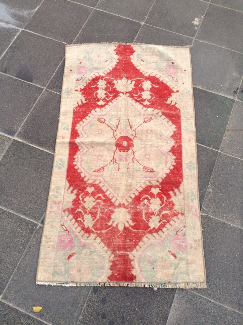 May include: A vintage rug with a cream background and a red floral design. The rug has a fringed edge and is in good condition.