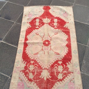 May include: A vintage Turkish rug with a red and cream color scheme. The rug has a floral pattern with a central medallion. The rug is in good condition with some wear and tear.