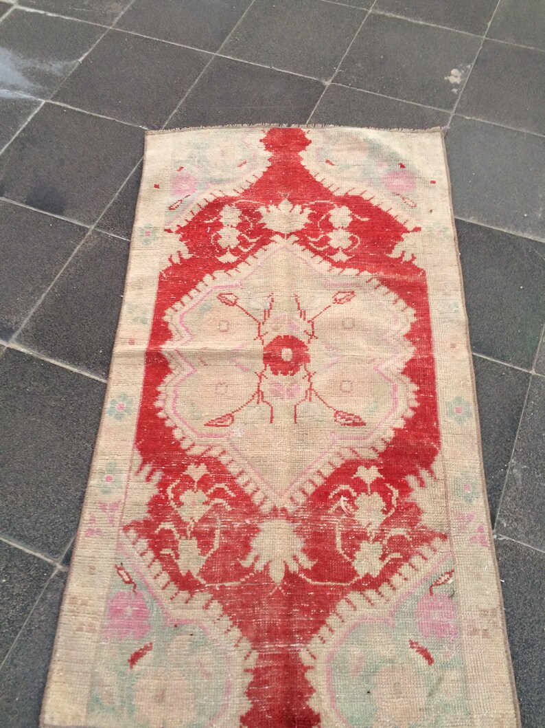 May include: A vintage Turkish rug with a red and cream color scheme. The rug has a floral pattern with a central medallion. The rug is in good condition with some wear and tear.
