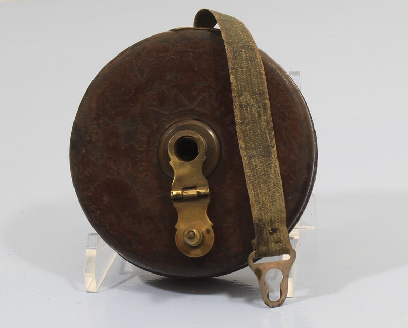 May include: A vintage wooden tape measure with a brass winding mechanism and a leather strap. The tape measure is brown and has a worn, antique look.
