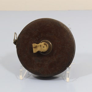 May include: A vintage, brown leather tape measure with a brass winding mechanism. The tape measure has a worn, aged appearance and is marked with the number "1681".