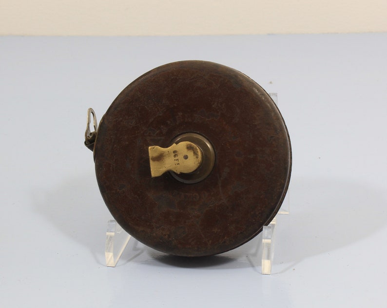 May include: A vintage, brown leather tape measure with a brass winding mechanism. The tape measure has a worn, aged appearance and is marked with the number "1681".