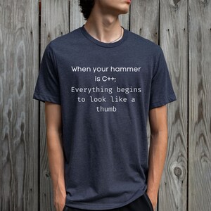 May include: A dark blue t-shirt with white text that reads "When your hammer is C++, Everything begins to look like a thumb."