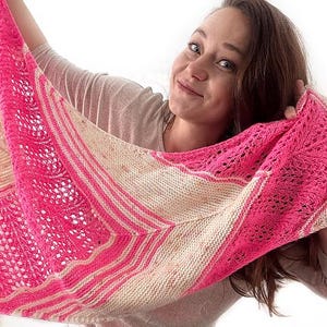 Peut inclure: Un châle tricoté à la main, rose et beige. Le châle présente un motif de dentelle détaillé et des rayures. La femme sur l'image tient le châle, mettant en valeur son design et ses couleurs.