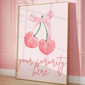 Puede incluir: Una impresión enmarcada en rosa y dorado con una ilustración de acuarela de dos cerezas atadas con una cinta rosa. El texto "your sorority here" está escrito en cursiva rosa debajo de las cerezas.