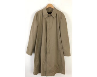 Könnte beinhalten: Ein beiger Trenchcoat mit Knopfleiste und zwei Taschen. Der Mantel hat ein klassisches Design und ist aus einem leichten Stoff gefertigt.