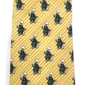 May include: A yellow silk tie with a repeating pattern of cartoon chefs wearing green aprons. The tie has thin yellow stripes.