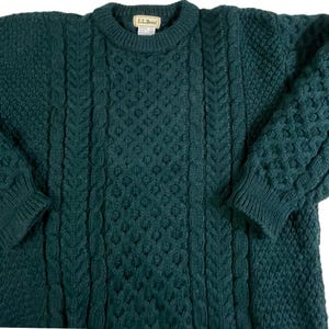May include: A dark green cable knit sweater with a crew neck and the L.L.Bean logo on the front.