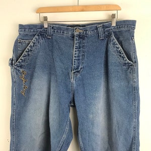May include: Blue denim carpenter shorts with a brown embroidered "Bugle Boy" logo on the left leg.