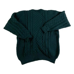 May include: A dark green knitted sweater with a cable knit pattern.