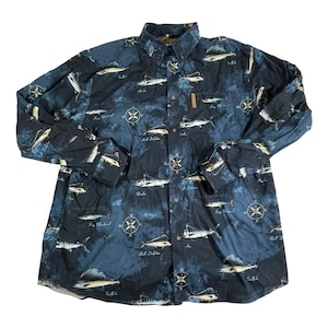May include: A long-sleeved button-down shirt with a navy blue background and a pattern of various fish, compasses, and text. The shirt has a button-down collar and a small pocket on the chest.